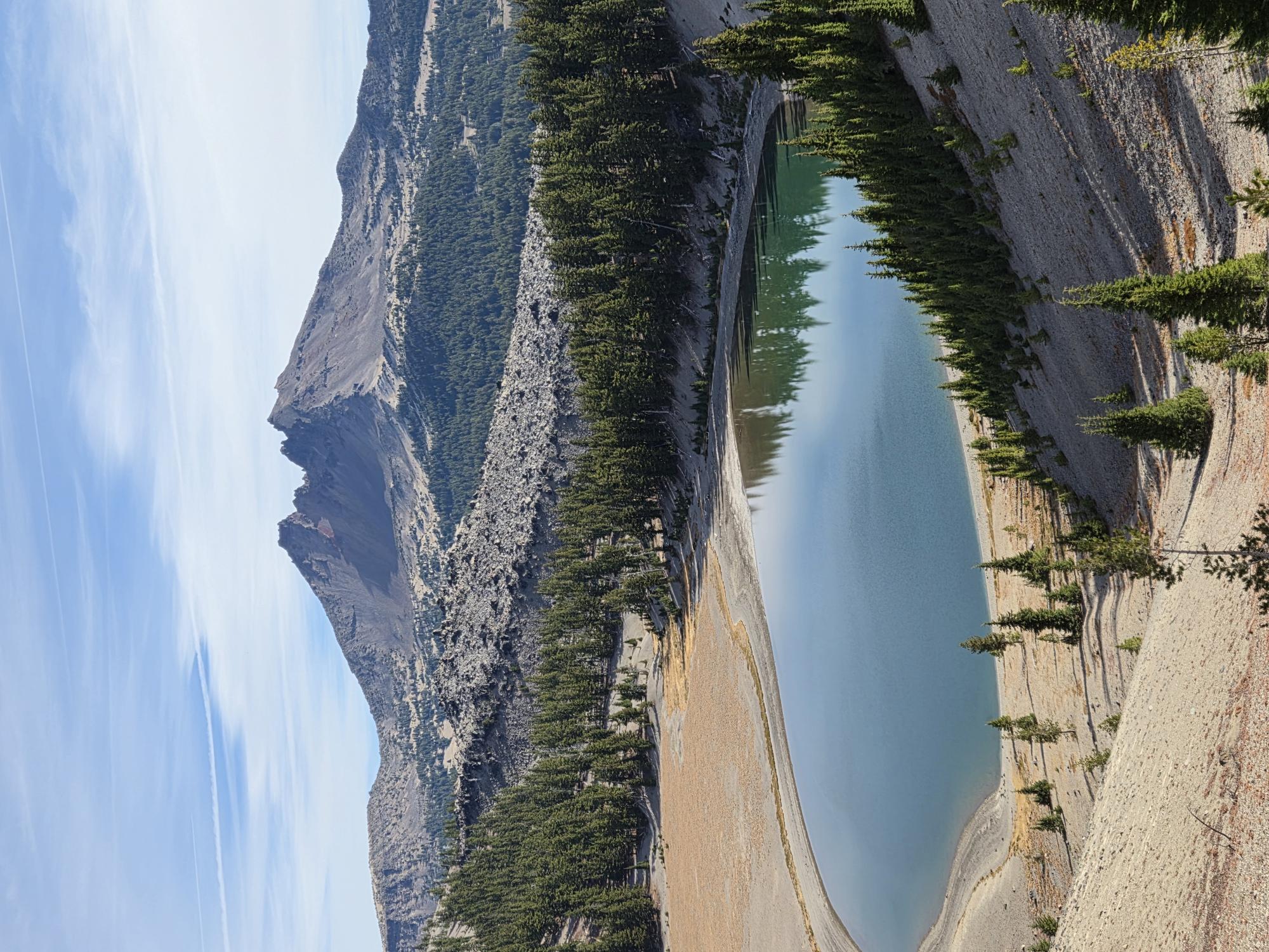 Looking down on Moraine Lake with Broken Top beyond it. Alt text: Elevated view of Moraine Lake and Broken Top from a volcanic moraine near South Sister.